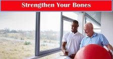 Strengthening Your Bones: The Best Exercises for Bone Health. Picture of a young black male physical therapist working with an older caucasian male with a large red exercise ball.